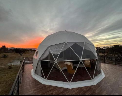 a tent on a deck with a sunset in the background at El Gato Glamping con vista al valle in Huasca de Ocampo