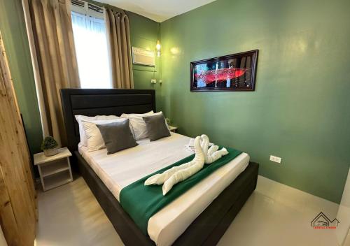 a bedroom with a bed with a green wall at Palawan 1BR Summer Get-away Deluxe with Balcony FREE Pool and Gym - T2 6 Diamond in Puerto Princesa City
