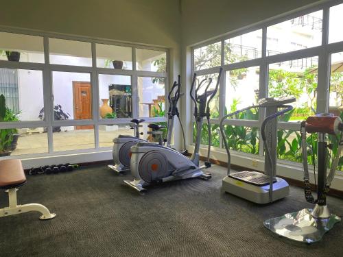 a gym with treadmills and elliptical machines and windows at Sala Siem Reap Hotel in Siem Reap