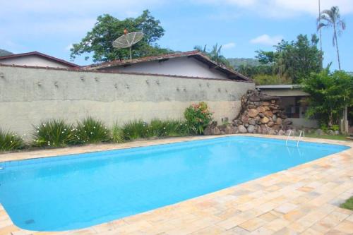 a swimming pool in front of a house at Villa Tavares - casa com piscina na praia da Lagoinha in Ubatuba