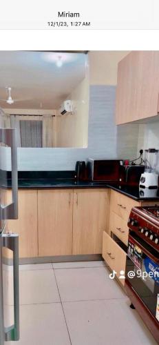 a kitchen with wooden cabinets and black counter tops at 3RD Ave. Beach Apartment Nyali, Mombasa, North Coast in Nyali