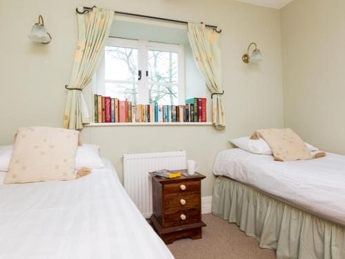 a bedroom with two beds and a window with a book shelf at 2 Bed in Chapel-en-le-Frith PK606 in Chapel en le Frith