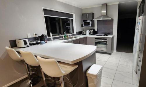 una cocina con encimera blanca y sillas. en A room in a homestay, en Upper Hutt