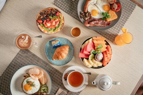 a table topped with plates of breakfast foods and coffee at Maison Aurelia Sanur, Bali - By Préférence in Sanur