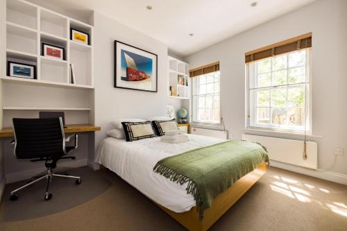 a bedroom with a bed and a desk and a chair at London Is Yours - 2 Bedroom in Kensington in London