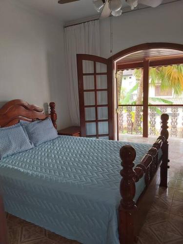 a bedroom with a bed with a wooden frame and a window at Castelinho do Felix Guarujá Pernambuco in Guarujá