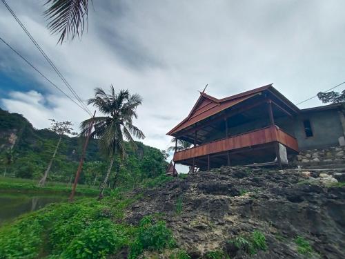 RAMMANG-RAMMANG HOUSE في Maros: مبنى فوق تلة فيها نخلة