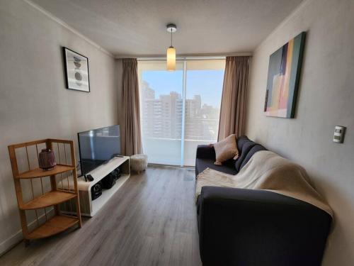 a living room with a couch and a large window at Acogedor Apartamento en Centro de Santiago. in Santiago