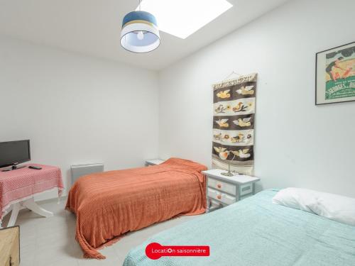 une chambre avec deux lits, un bureau et une télévision dans l'établissement Échoppe confortable à 200m de la plage - 4 pers, patio, cuisine équipée - FR-1-535-27, à Châtelaillon-Plage