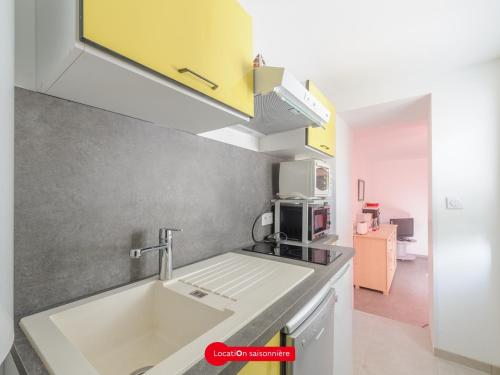 une cuisine avec un évier et un micro-ondes dans l'établissement Appartement T2 à 50m de la plage avec cour, Wifi et équipements bébé – 4 pers, Châtelaillon-Plage - FR-1-535-17, à Châtelaillon-Plage