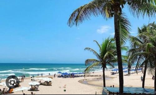 uma praia com palmeiras e o oceano em Maresia 7B em Salvador