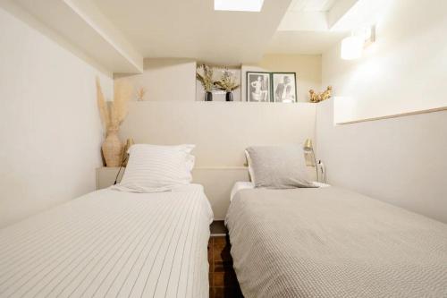 two beds in a room with white walls at La Suite privée des Chevaliers in Paris