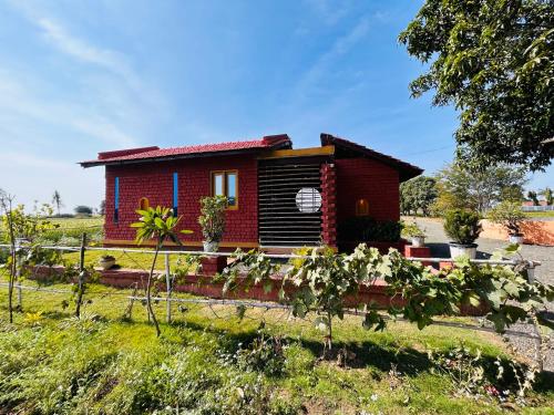 een klein rood huis in het midden van een veld bij Girija Homestay in Shamsgarh