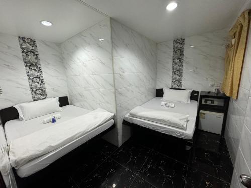 Habitación pequeña con 2 camas y paredes blancas. en Om Guest House, en Hong Kong