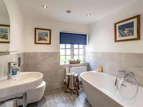 a bathroom with a white tub and a sink at 3 Bed in Ross-on-Wye 75491 in Llangarren