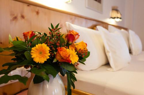 a white vase with a bouquet of flowers on a bed at Familien- und Wellnesshotel "Viktoria" in Oberstdorf