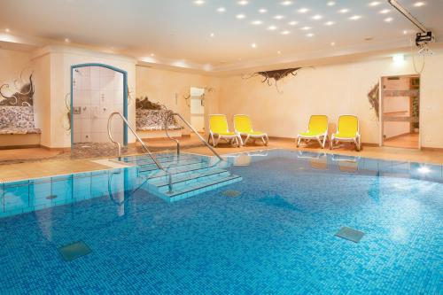 a swimming pool with yellow chairs and chairs in a room at Familien- und Wellnesshotel "Viktoria" in Oberstdorf