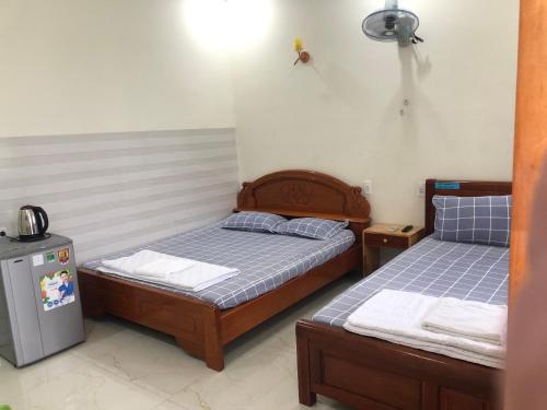 two twin beds in a room with a refrigerator at Homestay 05 in Vung Tau