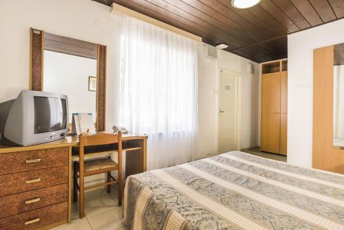 una camera con letto e scrivania con TV di Rooms Savudrija Plava Laguna a Savudrija