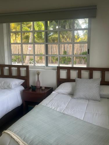 Un dormitorio con dos camas y una gran ventana. en Casa ALBU Telchac Puerto de Abrigo, en Telchac Puerto