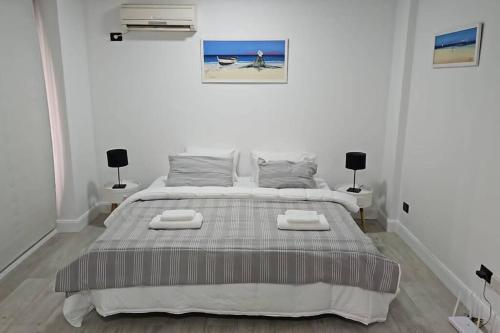 a white bedroom with a large bed with two lamps at Hermoso apartamento en el corazón de Palermo - Cerca de todo in Buenos Aires
