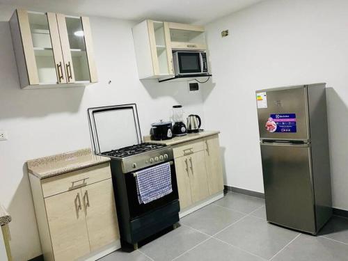 a kitchen with a stove and a refrigerator at Acogedora casa en Pisco a 20 min de paracas in Pisco