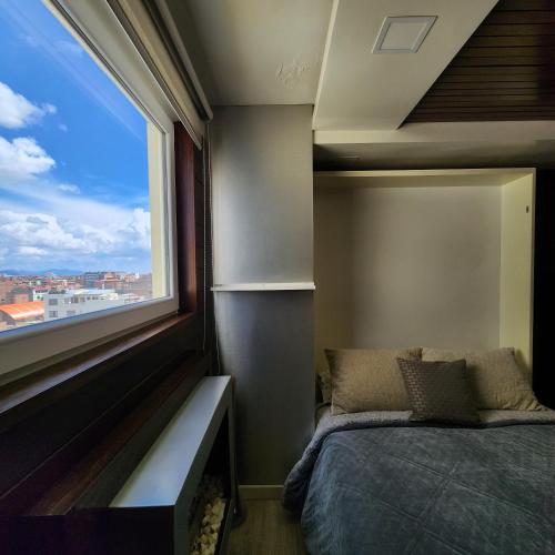 a bedroom with a bed and a large window at Torre Bella apartment in Oruro