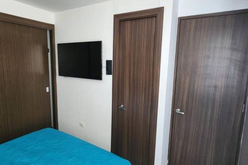 a bedroom with two doors and a tv and a bed at Apto con tres aires en villa campestre Barranquilla in Barranquilla