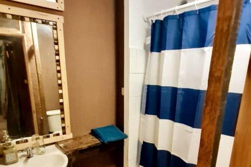 baño con cortina de ducha azul y blanco en Borde rio, Eco-Cabaña Jararankhu en Vicuña