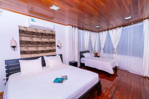 a bedroom with two beds and a wooden ceiling at EXCLUSIVE CONDO GALAPAGOS and BEYOND 1 in Puerto Ayora