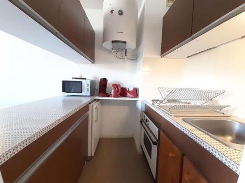 une petite cuisine avec un évier et un micro-ondes dans l'établissement Studio cosy 4 pers avec balcon et kitchenette au Pla d'Adet - FR-1-457-339, à Saint-Lary-Soulan