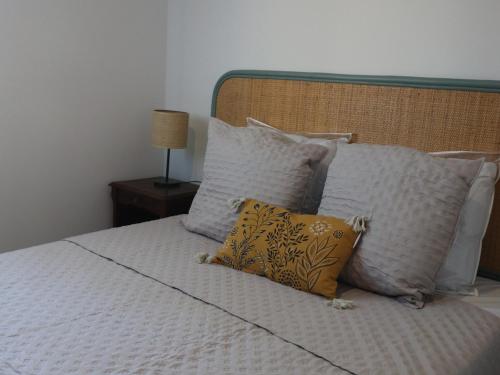 - un lit avec des oreillers blancs et un oreiller jaune dans l'établissement Charmant T2 avec terrasse pour 4 pers, Sète – parking sécurisé, proche commodités - FR-1-472A-292, à Sète