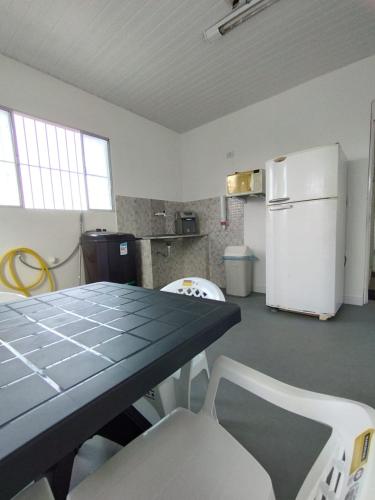 uma cozinha com uma mesa e um frigorífico branco em JM Alojamento em Igarassu