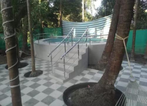 a pool with stairs and a tree on a tiled floor at Bhumi Holiday Home in Alibaug