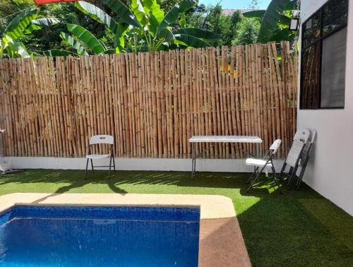 a swimming pool with two chairs and a wooden fence at Departamento Amueblado con Alberca Pedregal D in Tamasopo