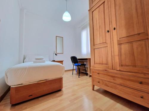 a bedroom with a bed and a wooden cabinet at Reina Cristina, 3 dormitorios individuales en Atocha-Retiro in Madrid