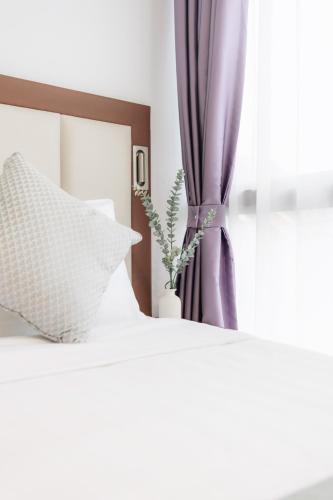 a bed with white pillows and a purple curtain at Santa Grand Hotel East Coast a NuVe Group Collection in Singapore