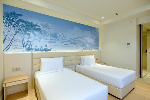 two beds in a room with a painting on the wall at Cititel Express Kota Kinabalu in Kota Kinabalu