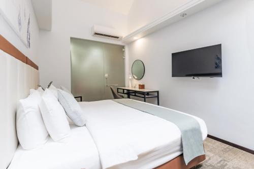 a bedroom with a white bed and a television at Santa Grand Hotel East Coast a NuVe Group Collection in Singapore