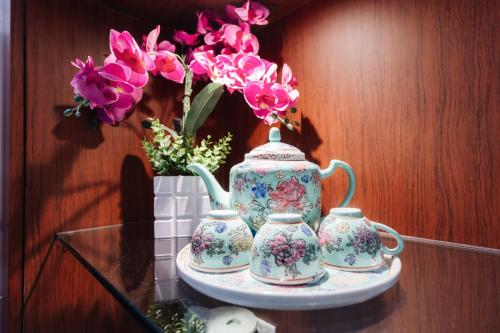 two tea pots and a vase with flowers on a table at Santa Grand Hotel East Coast a NuVe Group Collection in Singapore