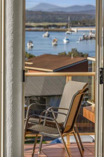 a chair on a balcony with a view of a harbor at Baywatch - Unit 6 in Merimbula
