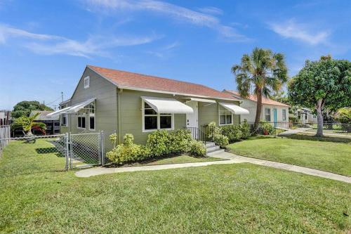 a house with a fence in front of a yard at Palm Wave Says - 5 Star - Quiet Area - Stocked in West Palm Beach