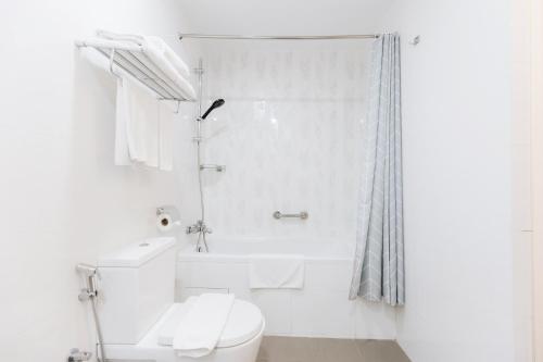 a white bathroom with a toilet and a shower at Santa Grand Hotel East Coast a NuVe Group Collection in Singapore