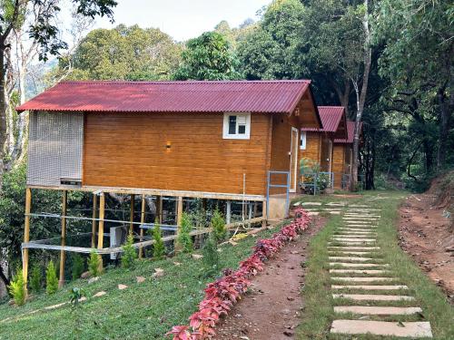 a small wooden house with a red roof at Coorg Jungle Mist in Madikeri