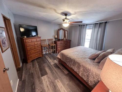 a bedroom with a bed and a flat screen tv at Bern's Summit Solitude: Stream-Front Serenity in Confluence