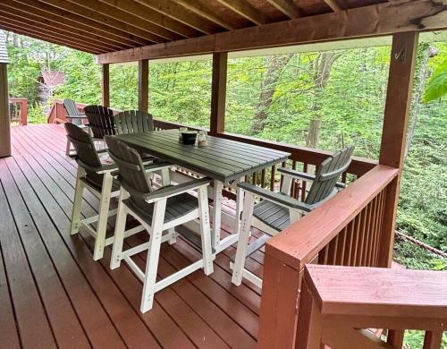 a wooden deck with a table and chairs on it at Bern's Summit Solitude: Stream-Front Serenity in Confluence