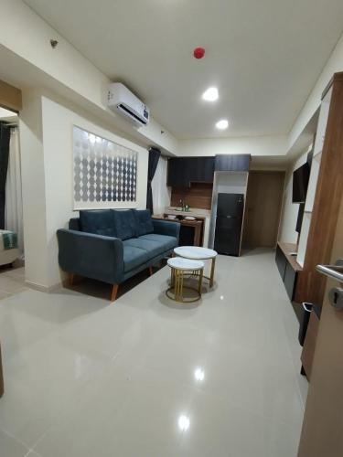 een woonkamer met een blauwe bank en een tafel bij Classy and Elegance Apartment at Meikarta Tower Silverlake 