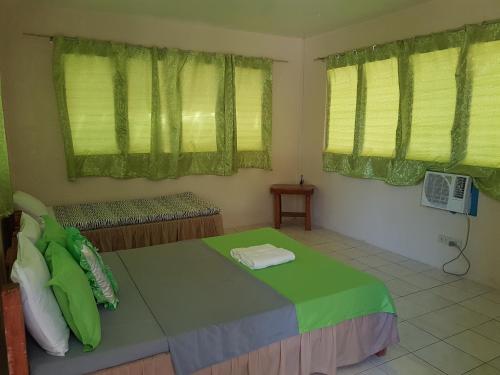 a bedroom with a bed with green sheets and windows at Aglicay Beach Resort in Romblon