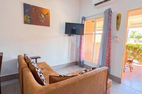 a living room with a couch and a tv at Villa Paraíso banano 9, near to the beach & Pool in Jacó