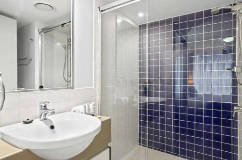 a bathroom with a sink and a shower with blue tiles at Cozy Unit in the heart of Brisbane in Brisbane
